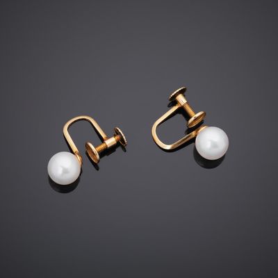 a pair of pearl and gold earrings on a black background