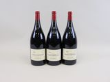 trois bouteilles de vin rouge sont alignées sur une surface blanche