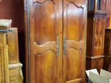 une grande armoire en bois dans une pièce où se trouvent de nombreux autres meubles