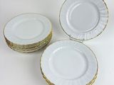 four white plates with gold rims stacked on top of each other