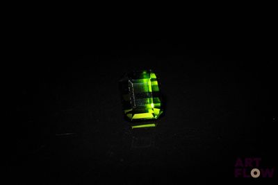 un gros plan d'un anneau vert sur une surface noire