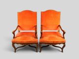 pair of orange upholstered chairs with arms and legs