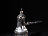 an antique silver coffee pot sitting on top of a black table