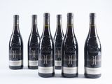 six bottles of wine are lined up on a white surface