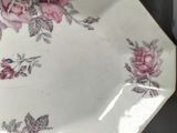 a white plate with pink roses on it sitting on a table