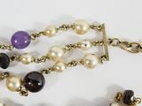 purple and white pearls and gold necklace on a white surface