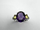 a close up of a ring with an amethorate and yellow sapphire stones
