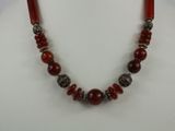 a close up of a necklace with red beads on a mannequin