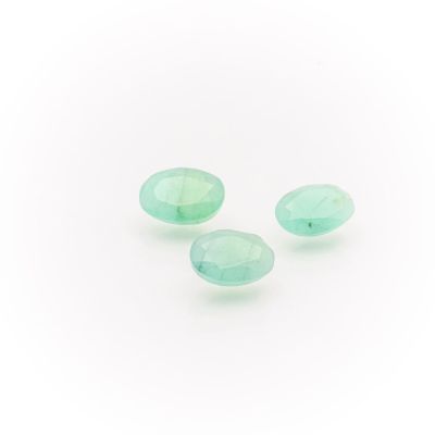 a group of three green glass tear shaped beads on a white surface