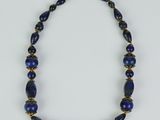 a necklace with blue beads and gold accents on a white background