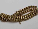 gros plan d'un bracelet en chaîne en or sur une surface blanche