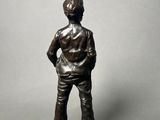 a bronze statue of a man standing with his hands on his hips