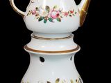 une théière blanche bordée d'or et décorée de fleurs