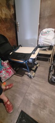 une femme assise sur une chaise dans une pièce où se trouvent des bagages