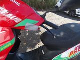 a red scooter parked in a parking lot next to a white car