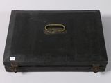 an old black suitcase with a metal handle on a white surface