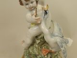 a figurine of a boy with a bird on a pedestal