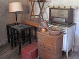a table with a lamp, a chair, and an old radio in a room