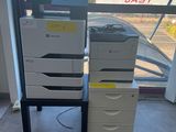 a stack of printer ' s sitting on a table in front of a window