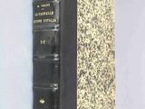 an old book with a black cover sitting on top of a white wall