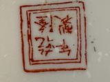 une assiette rouge et blanche avec une écriture chinoise dessus