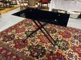 une table noire avec un plateau en verre, posée sur un tapis