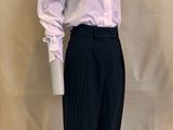 un mannequin masculin vêtu d'une chemise blanche et d'un pantalon noir à fines rayures