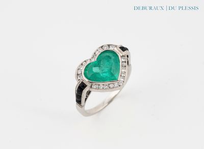 une bague en forme de cœur sertie d'une émeraude et de diamants, sur fond blanc