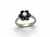 une image représentant une bague ornée d'une fleur en diamants et saphirs sur fond blanc
