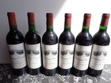 six bottles of wine are lined up on a table