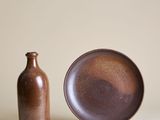une assiette marron à côté d'une bouteille marron posée sur une table