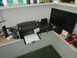 un bureau sur lequel se trouvent un ordinateur, une imprimante et d'autres appareils électroniques