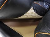 a black leather couch with orange trims and pillows