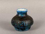 a small blue vase sitting on a gray surface