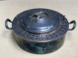 a large metal pot with a lid on a table