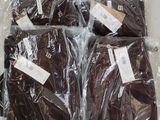 six brown shirts wrapped in plastic bags on a table