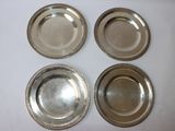 four silver plates with beaded rims on a white surface
