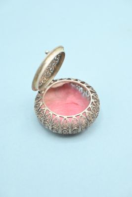 an image of a small gold locke with a pink glass inside