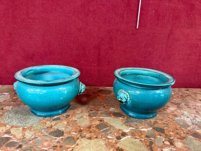 deux vases bleus posés sur une table, avec un mur rouge en arrière-plan