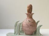 un vase rose orné d'une feuille verte sur un fond blanc
