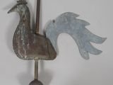 a metal rooster on a pole on the wall