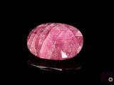 a close up of a pink stone on a black surface