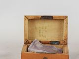a small wooden box with a purple cloth inside of it