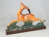 a figurine of a deer that is running in the grass