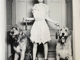 a black and white photo of a woman and two dogs