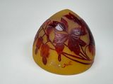 un vase jaune orné de feuilles rouges, posé sur un fond blanc