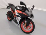 une moto noire et orange garée dans une pièce blanche