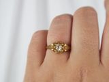 a woman ' s hand holding a gold ring with three diamonds