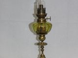 une lampe à huile ancienne en laiton, surmontée d'un abat-jour en verre vert