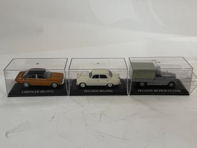 trois petites voitures miniatures sont exposées dans une vitrine posée sur une surface blanche